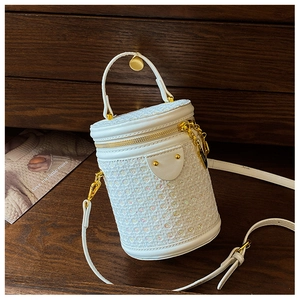 Detail of white sequin cylinder bag with gold hardware and woven tweed texture
