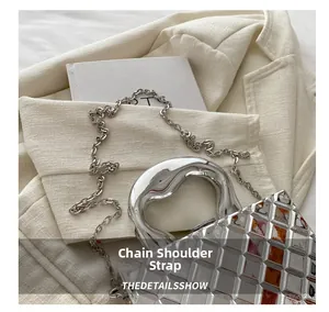Detail of silver quilted handbag with round metal handle and delicate chain strap