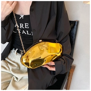 Close-up of golden irregular acrylic evening clutch bag with high mirror liquid shine