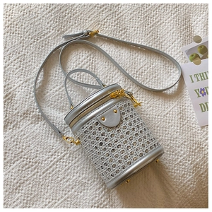 Close-up of a silver rhinestone cylinder bag with gold zippers and woven mesh texture