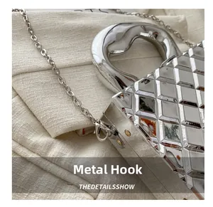 Close-up of silver mirror finish quilted handbag with metallic handle and chain hook detail