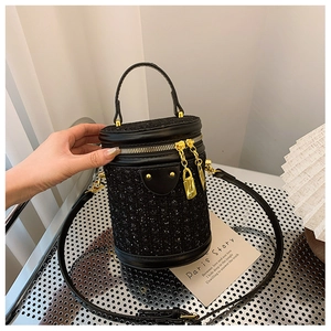 Detailed top view of black cylinder bucket bag with tweed texture and gold hardware