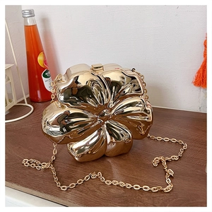 Close-up of golden flower shaped evening clutch bag with metallic plating and chain