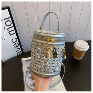 Silver rhinestone cylinder bag with gold lock detail and twin zippers shown in lifestyle setting