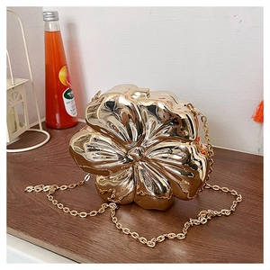 Close-up of a golden flower-shaped evening bag with a metallic chain on a table