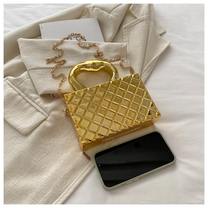 Detail of gold box clutch with quilted texture and hollow heart-shaped handle