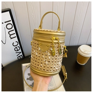 Detail of woven straw barrel bag with gold leather trim and glittering accents