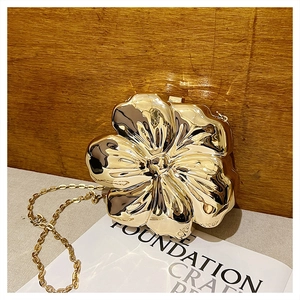 Detailed view of 3D gold flower clutch bag with reflective metal finish and chain strap
