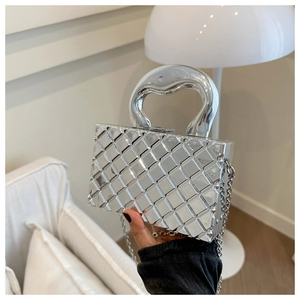 Detailed view of silver geometric quilted handbag with metallic handle and chain strap