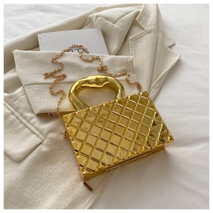 Macro shot of metallic gold box bag with diamond quilting and heart-shaped handle