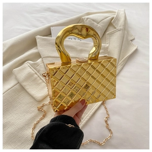 Close-up of golden quilted box clutch with metallic handle and elegant chain strap