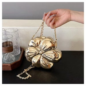 Detailed view of the 3D flower-shaped golden metal evening clutch with chain strap
