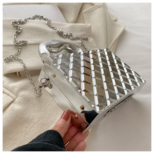Detail of silver metallic handbag with geometric rhombic texture and metal handle
