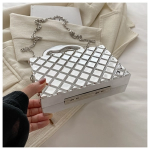 Macro view of silver quilted hardshell clutch bag featuring metallic chain and top handle