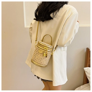 Detail of hollow-out woven cylinder bag with gold metal hardware and leather strap