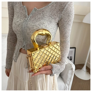 Detailed macro view of golden metallic quilted box bag with chunky round handle and chain