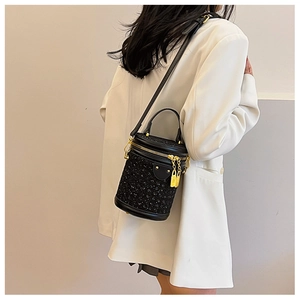 Detail of elegant black tweed cylinder bag with golden hardware and sequins on model