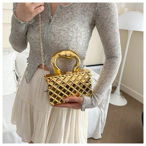 Close-up of golden quilted metallic handbag with unique shaped handle on a model
