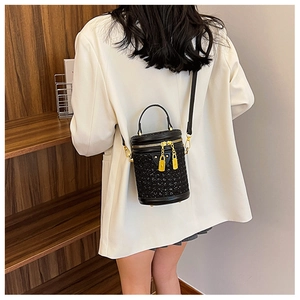 Detail of black cylindrical bucket bag with sparkling finish and gold zipper hardware