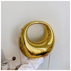 Détail du sac rigide doré brillant avec une bandoulière en chaîne métallique de luxe