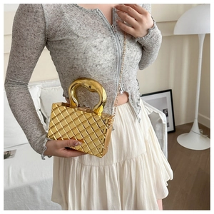 Detailed view of a gold metallic quilted box bag with an arched handle and chain strap