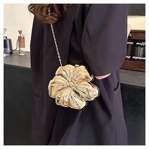 Detail of a golden flower-shaped evening clutch bag with metallic mirror finish