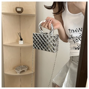 Close-up of silver quilted box bag with chunky metallic handle and chain strap