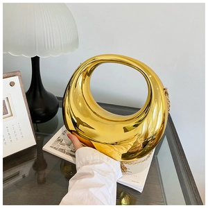 Détail d'un sac demi-lune doré brillant avec finition métallique et bandoulière chaîne