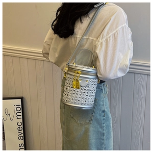 Detail view of silver rhinestone cylinder bucket bag worn on shoulder by a model