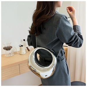 Détail d'un sac bandoulière argenté en forme d'anneau avec fine chaîne sur modèle