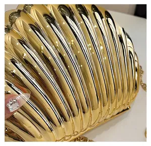 Macro shot of gold shell-shaped clutch bag with metallic texture and chain strap