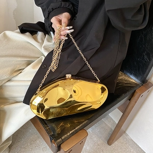 Irregular gold mirrored acrylic evening clutch bag with chain strap held by model