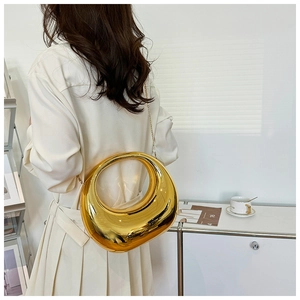 Sac demi-lune doré brillant avec bandoulière chaîne porté dans un décor minimaliste