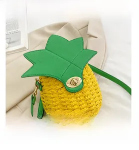 Close-up of pineapple-shaped woven straw bag with green leaf lid and gold metal lock