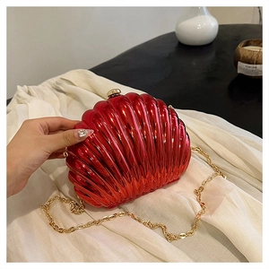 Dettaglio della pochette rossa a forma di conchiglia con finitura lucida e catena d'oro