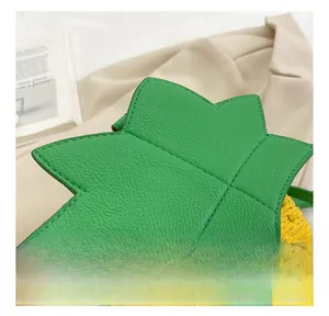 Detail of pineapple-shaped woven straw bag with green leaf flap and gold twist lock