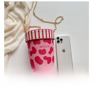 Detailed comparison of pink cow print milk cup bag next to a smartphone for size reference