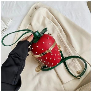 Close-up of strawberry-shaped handbag with pearl seeds and green leaf leather details
