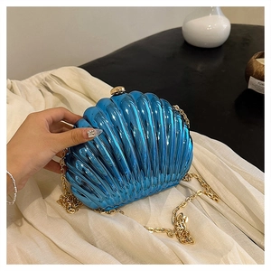 Dettaglio della borsa clutch blu metallizzato a conchiglia con catena dorata e fibbia
