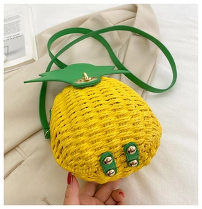 Detailed close-up of woven pineapple crossbody bag with green leaf accents and metal lock