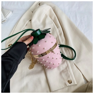 Detailed macro view of pink strawberry-shaped handbag with pearls and green leaf detail
