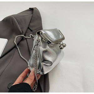 Detail of silver metallic pleated mini bag with ball clasp and chain on gray blazer