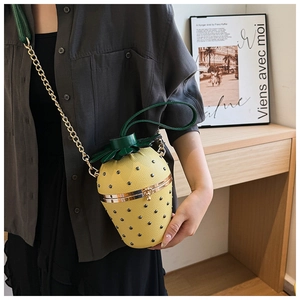 Macro shot of strawberry-shaped crossbody bag featuring yellow leather and leaf details