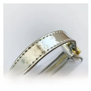 Close-up of shiny silver handle with white stitching and gold hardware detail