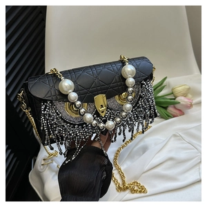Detail of black quilted shoulder bag featuring pearl handle and sparkling tassel fringe