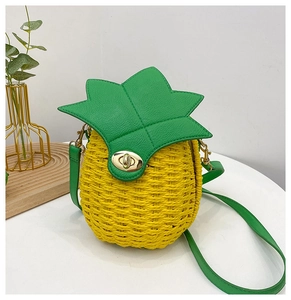 Detail view of a pineapple shaped woven bag with green leather leaves and gold swivel lock