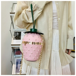 Detail of pink strawberry bag featuring white pearls and golden chain strap for women