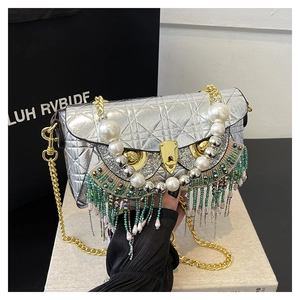 Detail of silver quilted owl-shaped bag with pearl accents and beaded tassels