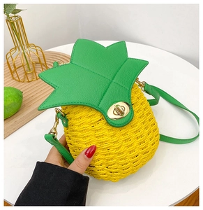 Detail of pineapple straw bag with green leather leaves and golden metal twist lock