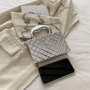 Silver metallic box clutch with quilted texture and chain strap next to smartphone